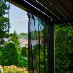A transparent mosquito net with a black frame mounted on a metal canopy.