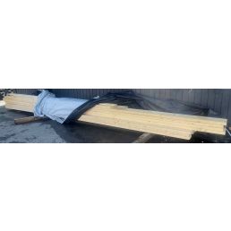The image shows a stack of rectangular sawn timber boards, partially covered with plastic. The boards appear to be approximately 45 × 145 mm and 45 × 195 mm in size.