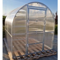 Växthuset Smal Tunnel PC 6mm, bredd 2m, tillverkat av transparent plast och med metallram, placerad på träpallar.