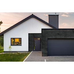 Kaasaegne ühepereelamu mustade ja valgete välisseinte ning suure integreeritud garaažiga.