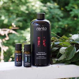 Musta pullo RENTO Arctic Berry saunatuoksu, 400 ml, kahden pienemmän öljypullon kanssa. Taustalla vihreitä lehtiä.