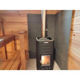 Must küttekolle koos terasest korstnaga, paigaldatud puidupaneelidega sauna, alumine osa kaitstud Tulekaitseplaadiga Homer A1.