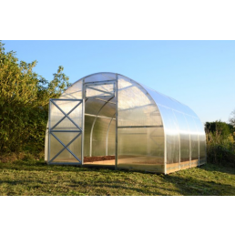 Bågformat växthus 'Kerttu PC' med 4 mm tjock polykarbonatbeläggning, bredd 3 m, längd 4 m, placerat på en grön gräsmatta.