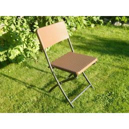 Brun hopfällbar stol i rotting med metallram, placerad på gräs.