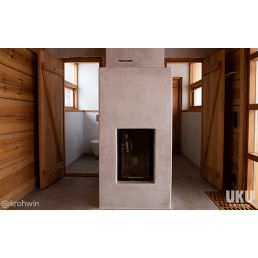 Moderni kylpyhuone, jossa on Tadelakt-pinnoite seinissä ja takassa, yhdistää puuseinäelementtejä.