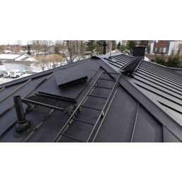 Musta harjakatto, varustettuna kattoturvatuotteilla, kuten tikkailla, lumiesteellä ja kattosillalla.